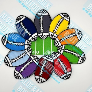 May include: A collection of colorful football-shaped patches arranged around a green field graphic. The patches are in various colors, including blue, yellow, orange, and red, with white stitching and black and white checkered end zones. The text "ALOE & MILK BOUTIQUE" is visible.