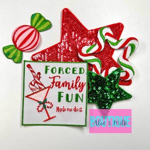May include: A set of five Christmas-themed iron-on patches. The patches feature a candy cane, a red star with sequins, a green star with sequins, a candy cane, and a white square patch with the text "Forced Family Fun Made me do it".