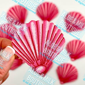 May include: Pink and white embroidered seashell patches. The seashells have a raised, textured design.