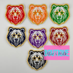 May include: Set of seven embroidered iron-on patches featuring a cartoon bear with star-shaped sunglasses in various colors, including red, orange, green, blue, purple, maroon, and black.