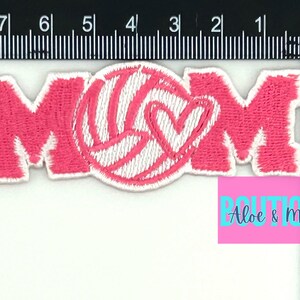 Pu&ograve; includere: Toppa da stiro ricamata rosa con la parola "MOM" e una pallavolo bianca con un cuore all'interno.