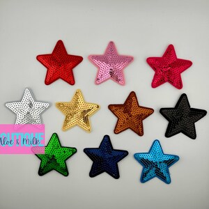 May include: Ten assorted sequin star iron-on patches in various colors, including red, pink, silver, gold, brown, black, green, and blue.  Boutique Aloe & Milk.