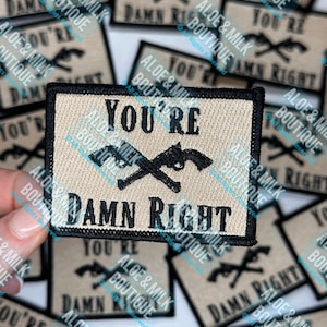 May include: A beige fabric patch with black stitching and a black and white graphic of two crossed pistols. The text "You're Damn Right" is printed in black letters.