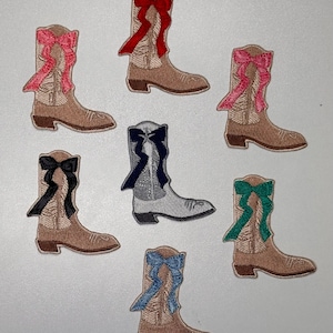May include: Set of eight embroidered iron-on patches featuring cowboy boots with different colored bows. The boots are all beige with a brown sole and a pointed toe. The bows are red, pink, black, navy blue, teal, and light blue.