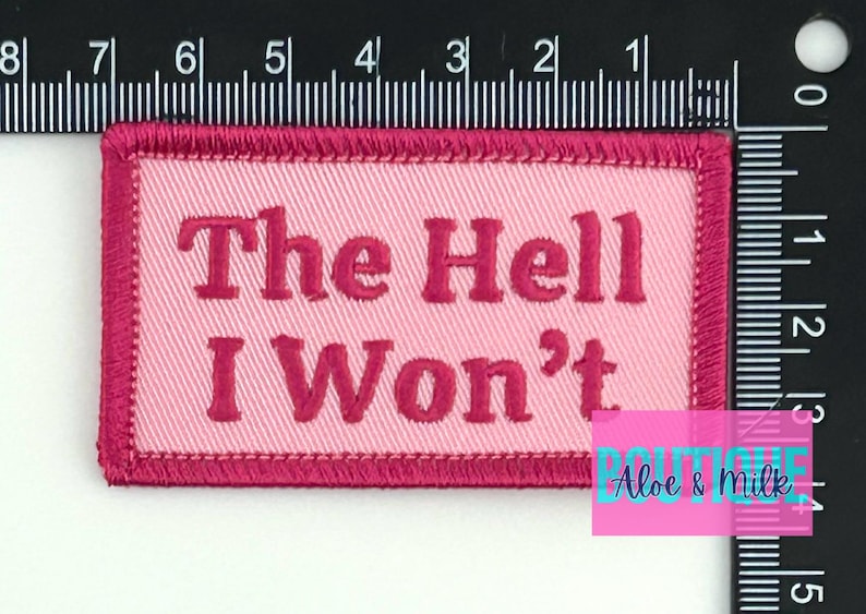 May include: Pink and red embroidered patch with the text "The Hell I Won't".