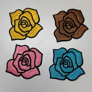 May include: Four embroidered iron-on patches featuring roses in different colors: yellow, brown, pink, and blue.