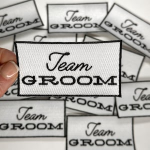 May include: White fabric patches with black embroidery that reads "Team Groom".