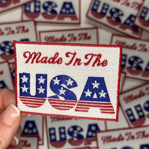 May include: A white embroidered patch with red and blue accents. The patch features the text "Made In The USA" with stars and stripes.