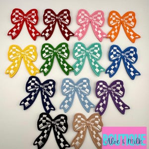 May include: A set of 10 colorful checkered bow patches. Each patch features a white checkered pattern on a different colored background. The colors include red, maroon, pink, orange, yellow, green, teal, blue, purple, and beige.