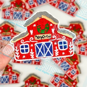 May include: Embroidered red barn patch with blue doors and windows, a gray roof, and a green wreath. The patch has the text "Mom & Dad" on it. The patch is surrounded by other patches.