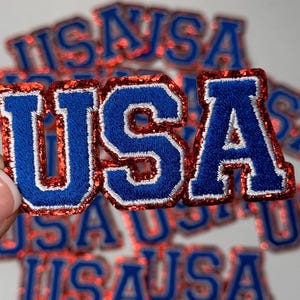 May include: Red, white, and blue glitter iron-on patches that spell out "USA".