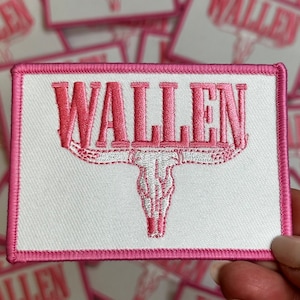 May include: Pink embroidered patch with the word "WALLEN" in a white background with a pink bull skull design.