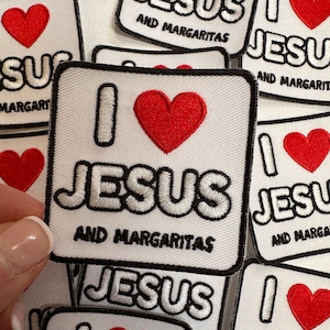 May include: White square patch with black border, embroidered with a red heart and the words "I JESUS AND MARGARITAS" in black and white. Several patches are visible.