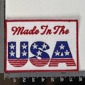 以下が含まれることがあります： 「Made In The USA」というテキストが書かれた、赤、白、青の刺繍パッチです。