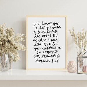 May include: A framed print with a white background and black text in a handwritten style. The text reads "y sabemos que a los que aman a Dios, todas las cosas les ayudan a bien, esto es, a los que conforme a su prop&oacute;sito son llamados. Romanos 8:28"