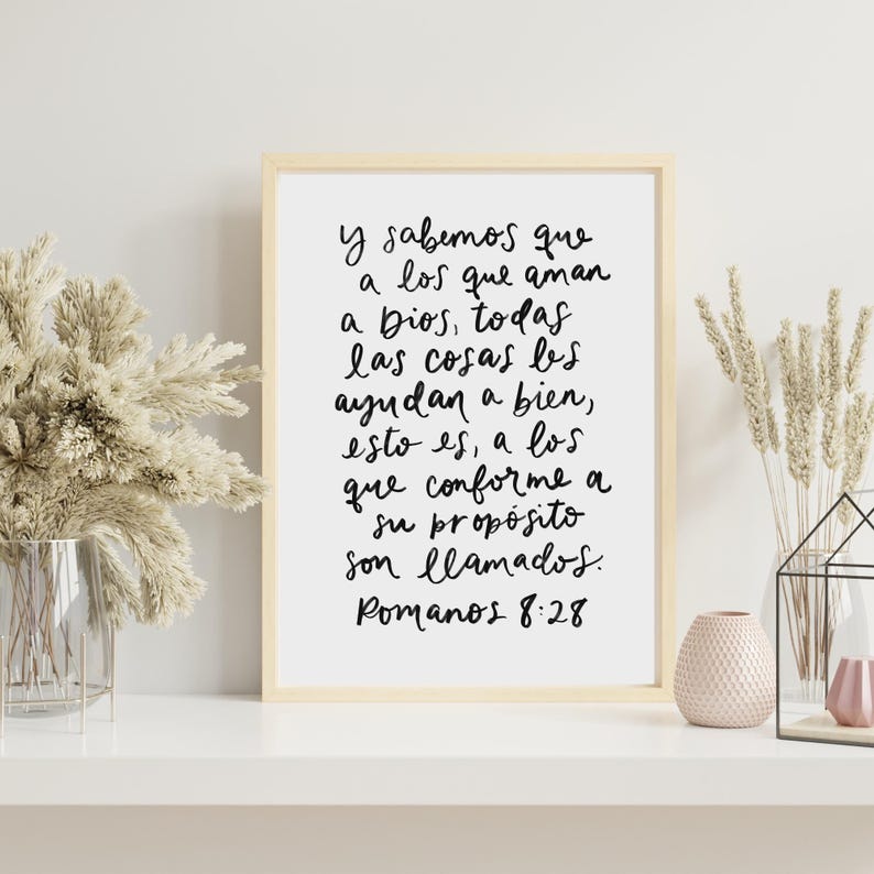 May include: A framed print with a white background and black text in a handwritten style. The text reads "y sabemos que a los que aman a Dios, todas las cosas les ayudan a bien, esto es, a los que conforme a su prop&oacute;sito son llamados. Romanos 8:28"