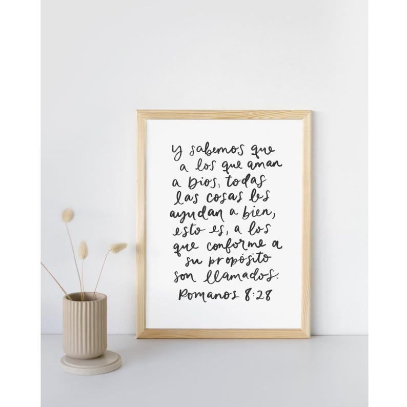 May include: A framed print with a white background and black handwritten text in Spanish. The text reads "Y sabemos que a los que aman a Dios, todas las cosas les ayudan a bien, esto es, a los que conforme a su prop&oacute;sito son llamados. Romanos 8:28"