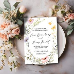 May include: Wedding invitation with a floral wreath design. The invitation reads "Welcome to the Wedding Mass Uniting Anne Beauchamp and Henry Randall in the Sacrament of Holy Matrimony, St. Paul's Cathedral, October 1, 20XX".