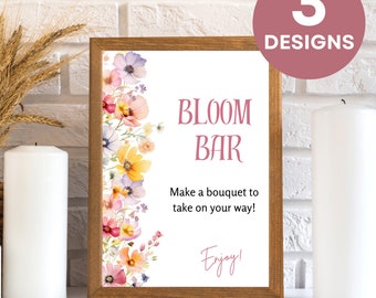 May include: A framed sign with the text "BLOOM BAR" and "Make a bouquet to take on your way!" in pink. The sign is decorated with watercolor flowers and the words "3 DESIGNS" in a circle.