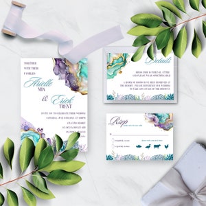 May include: Wedding invitation suite with a teal, purple, and gold watercolor design. The invitation features the couple's names, "Arielle Mia & Erick Trent", and the wedding date and location. The RSVP card includes a choice of meal options.