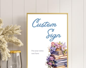 May include: A gold framed sign with the text "Custom Sign" in blue cursive lettering. The sign features a stack of books with a floral arrangement on top. The text "Put your extra text here" is below the books.