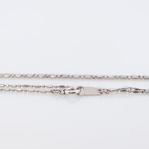 May include: A silver chain necklace with a lobster clasp fastening. The chain is made of small, round beads and rectangular links.
