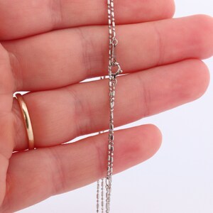 May include: A silver chain necklace with a lobster clasp fastening. The chain is made of small, round links.
