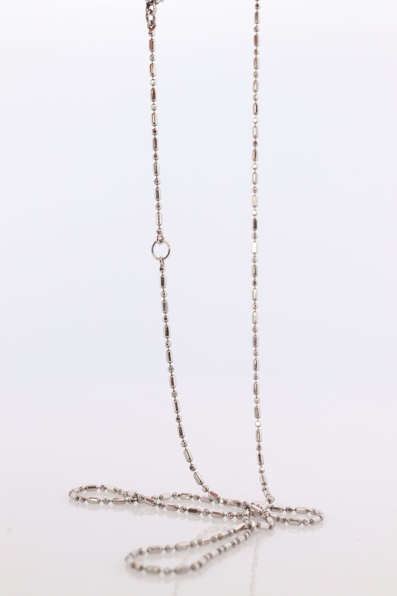 May include: A silver chain necklace with a small, round clasp. The chain is made of small, rectangular links.