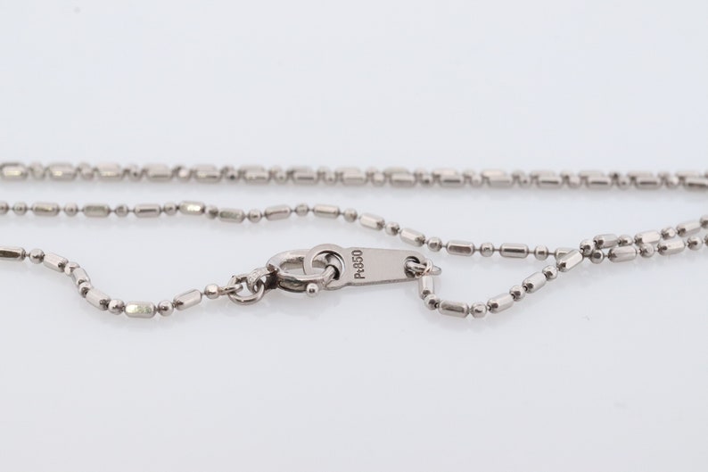 May include: A silver chain necklace with a lobster clasp and a tag that reads "P-950".