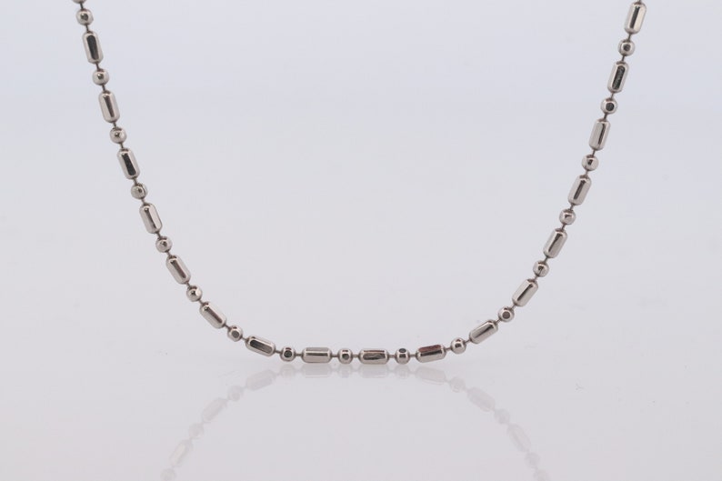 May include: A silver chain necklace with a simple, round and rectangular link design.
