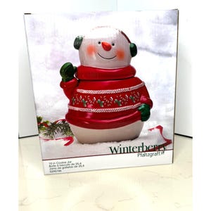 May include: A ceramic snowman cookie jar. The jar is white with a red sweater, green mittens, and earmuffs. The snowman has a carrot nose and a smiling face. The jar is 10 inches tall and is in a box with the text "Winterberry".