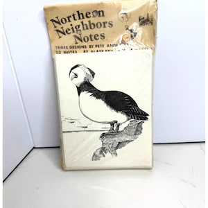 May include: A pack of 12 Northern Neighbors Notes stationery cards in clear plastic packaging. The top header features the text Northern Neighbors Notes and Three Designs by Pete Andrew. The front card displays a black and white illustration of a puffin.