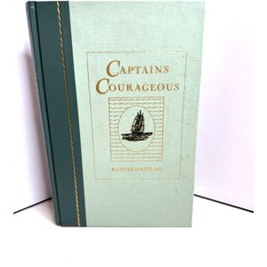 May include: A vintage hardcover book titled "Captains Courageous" by Rudyard Kipling. The book cover is light green with gold lettering and a black and white illustration of a ship.