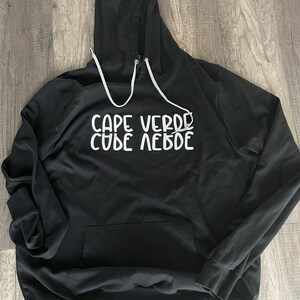 May include: Black hooded sweatshirt with the text "CAPE VERDE" written in white on the front.