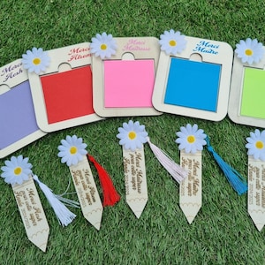 Peut inclure: Ensemble de six marque-pages en bois avec des notes adhésives colorées et un motif de marguerite. Chaque marque-page a un message différent, notamment "Merci Atsem", "Merci Maitresse", "Merci Resh" et "Merci Maitre".