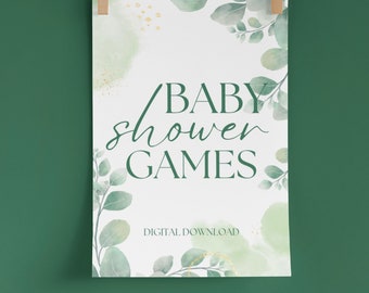 Könnte beinhalten: Ein weißes Schild mit dem Text "BABY shower GAMES" in grüner Schrift, verziert mit Aquarell-Stil grünen und goldenen Blattdesigns. Der Text "DIGITAL DOWNLOAD" steht darunter. Das Schild wird von Holzklammern an einer Schnur gehalten.