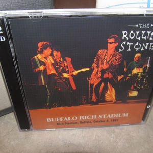May include: A 2-CD set of The Rolling Stones live at Buffalo Rich Stadium, October 8, 1997. The album cover features a concert photo of the band performing on stage. The text "THE ROLLING STONES" is displayed at the top.