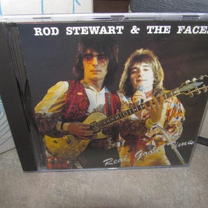 May include: CD case featuring Rod Stewart & The Faces. The cover shows two men, one with sunglasses and a guitar, the other with a microphone and guitar. The album title is "Real Good Time".