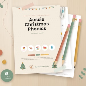 Peut inclure: Une pile de fiches pédagogiques intitulée Aussie Christmas Phonics avec une couverture beige présentant des icônes de Père Noël, kangourou, parasol, pastèque et tongs, accompagnée de trois crayons de couleur et d'éléments décoratifs de Noël.