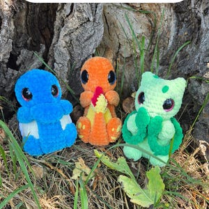May include: Three small plush toys made of blue, orange, and light green yarn, each featuring large black eyes. The blue toy is on the left, the orange one in the centre, and the light green one on the right. Text reads: Crochet Patttern Bundle.