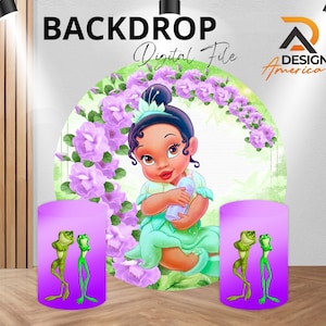 May include: A purple backdrop with a green circle featuring a cartoon baby princess with a crown and a green dress. The princess is holding a bottle. The circle is surrounded by purple flowers. Two purple cylinders with green frogs are in front of the backdrop.