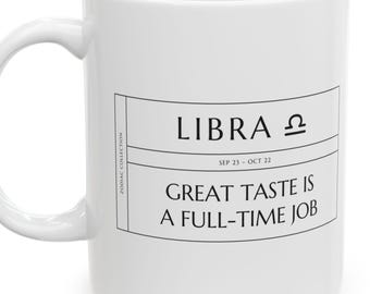 May include: A white ceramic mug featuring a black graphic design with the text LIBRA, the Libra zodiac symbol, the dates SEP 23 - OCT 22, and the phrase GREAT TASTE IS A FULL-TIME JOB, along with the vertical text ZODIAC COLLECTION.