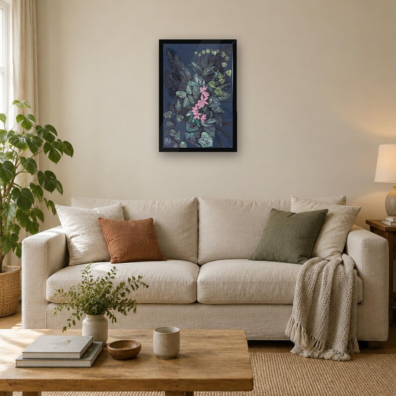 May include: A framed rectangular wall art piece featuring a dark blue background with a central cluster of pink flowers surrounded by textured green and dark foliage, encased in a simple black frame hanging on a neutral wall.