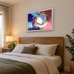 Puede incluir: Una pieza de arte mural rectangular enmarcada que presenta una pintura abstracta con una pincelada circular dorada central. La composici&oacute;n incluye remolinos vibrantes de azul profundo, magenta y blanco con goteos verticales en un marco claro.