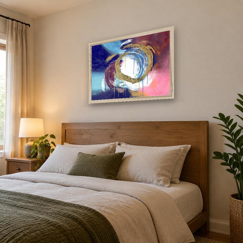 Puede incluir: Una pieza de arte mural rectangular enmarcada que presenta una pintura abstracta con una pincelada circular dorada central. La composici&oacute;n incluye remolinos vibrantes de azul profundo, magenta y blanco con goteos verticales en un marco claro.