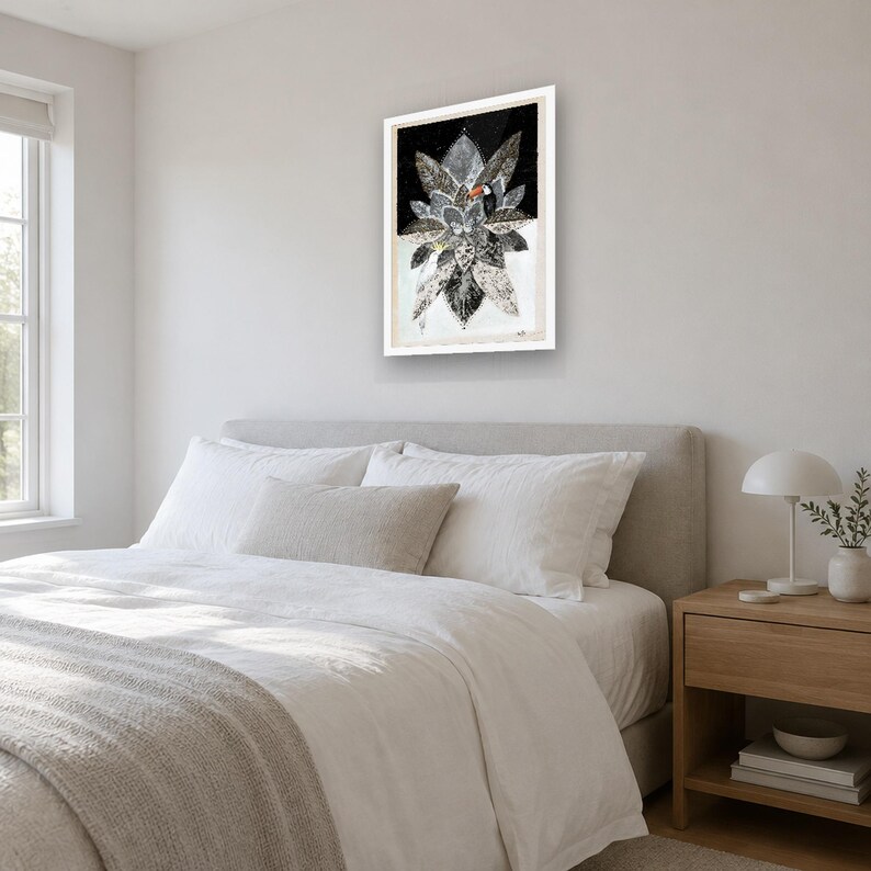 May include: A rectangular framed wall art piece featuring a central toucan with a bright orange beak, surrounded by a cluster of stylized black, white, and gray leaves against a dark background, all enclosed in a simple white frame.