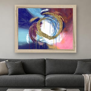 Puede incluir: Una pieza de arte mural rectangular enmarcada que presenta una pintura abstracta con una pincelada circular dorada central. La composici&oacute;n incluye remolinos vibrantes de azul profundo, magenta y blanco, con gotas de pintura verticales hacia abajo.