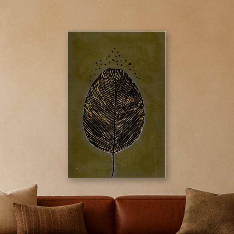 May include: A rectangular wall art print featuring a large, central leaf illustration with black and gold textured veins against a solid olive green background. Above the leaf, a series of small black dots form an arching pattern.