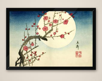 May include: A framed print featuring a dark, gnarled tree branch with vibrant pink blossoms set against a large, pale yellow full moon. The background transitions from a deep blue at the top to a light cream at the bottom, with black Japanese calligraphy and a red square seal stamp on the right side.