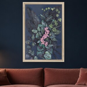 May include: A framed wall art piece featuring a dark navy blue background with a central cluster of deep green, textured foliage and a vertical arrangement of five light pink, five-petaled flowers. The frame is a light, natural wood color.